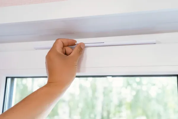 Hand die een ventilatie rooster open schuift van een raam