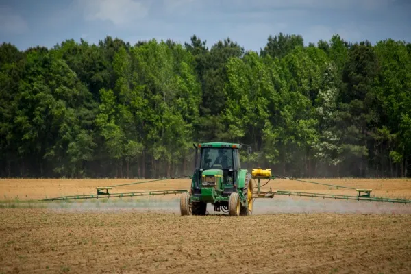 Groene tractor die land aan het besproeien is