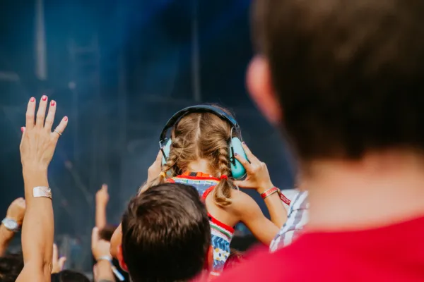 Meisje met koptelefoon op de schouders van een volwassene op een festival