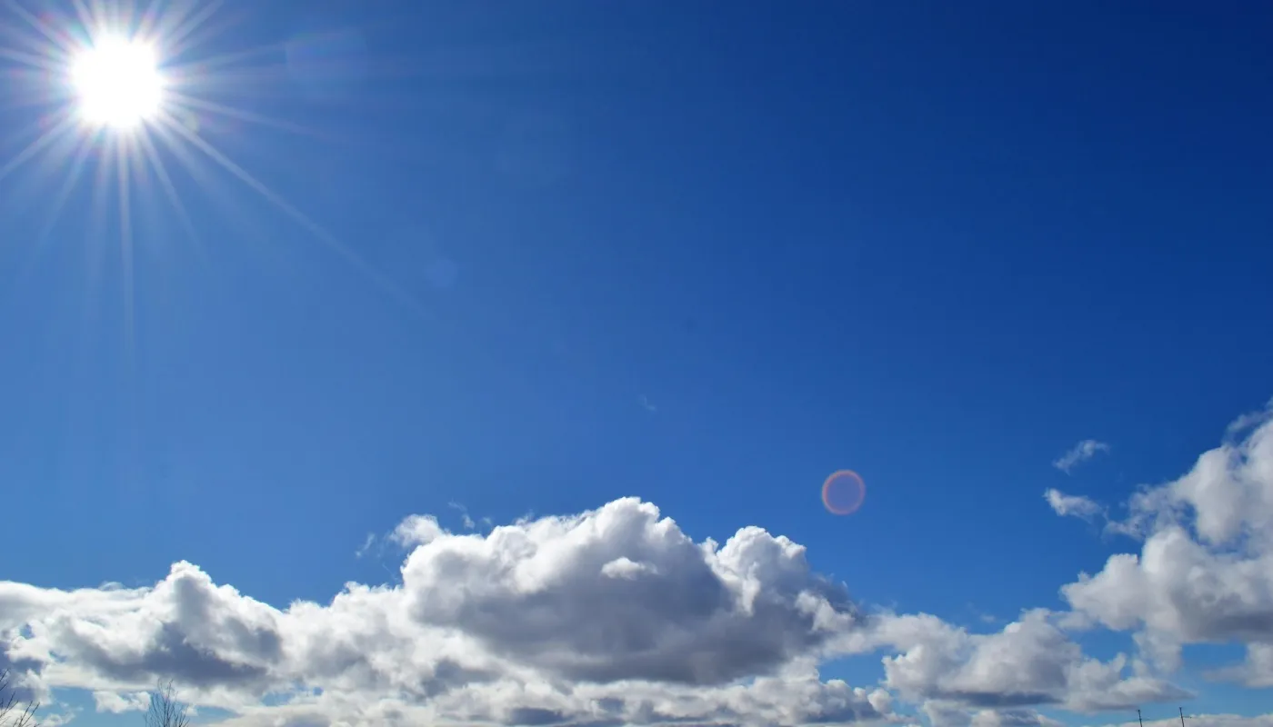 Blauwe lucht met witte wolken en de zon