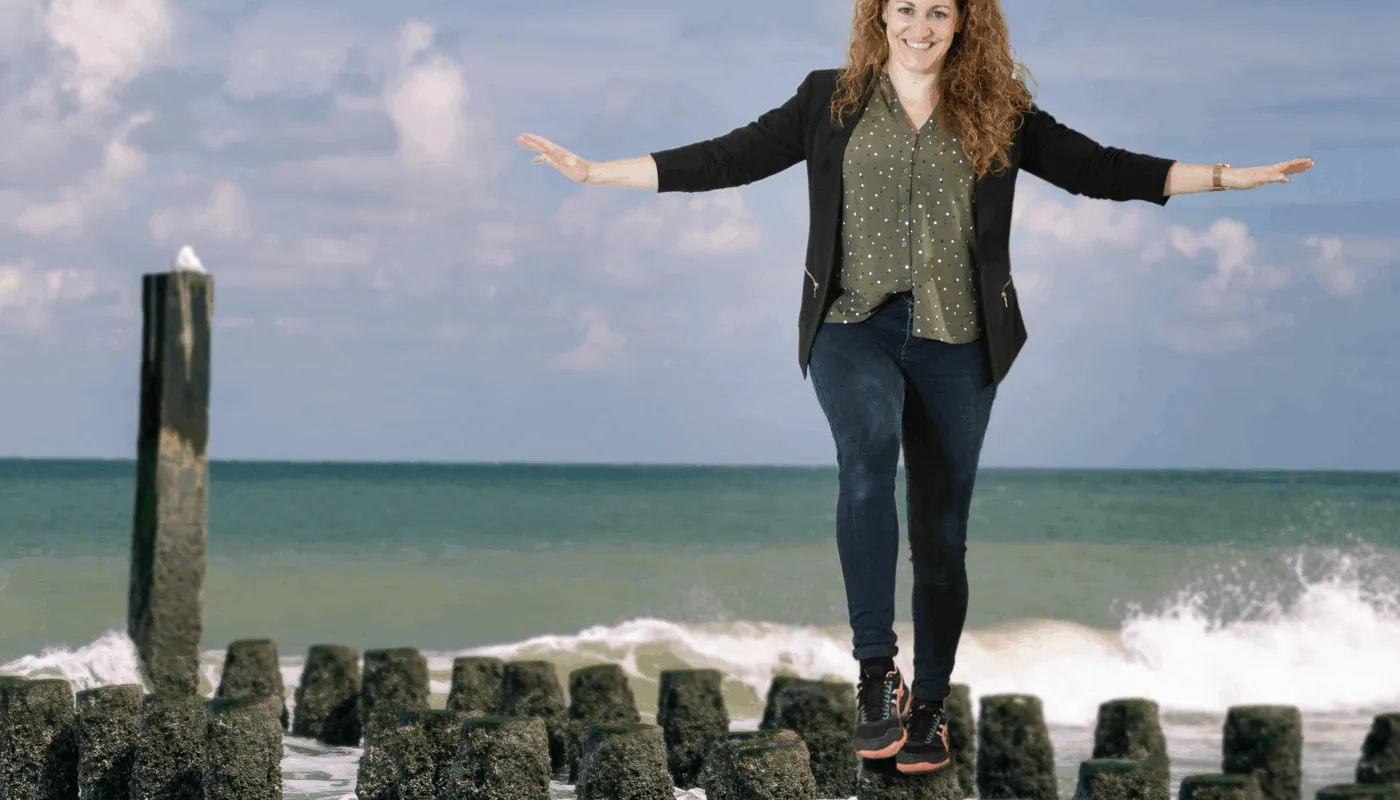 Bewerkte foto van Ellen Jansen. Op de foto is Ellen te zien op een paalhoofd ergens op een Zeeuws strand. Achter haar zie je een golf omslaan en zit een (vermoedelijk) meeuw op een hoge paal.