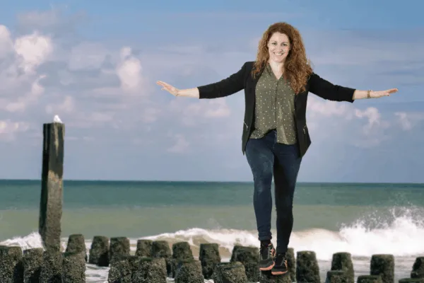Bewerkte foto van Ellen Jansen. Op de foto is Ellen te zien op een paalhoofd ergens op een Zeeuws strand. Achter haar zie je een golf omslaan en zit een (vermoedelijk) meeuw op een hoge paal.