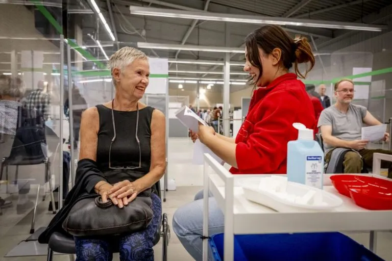GGD medewerker geeft oudere dame een vaccinatie in de bovenarm