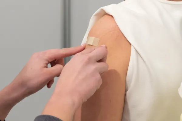 er wordt een pleister geplakt op een bovenarm na een vaccinatie