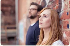 Man en vrouw staan met de rug tegen een muur en staren voor zich uit in het niets.